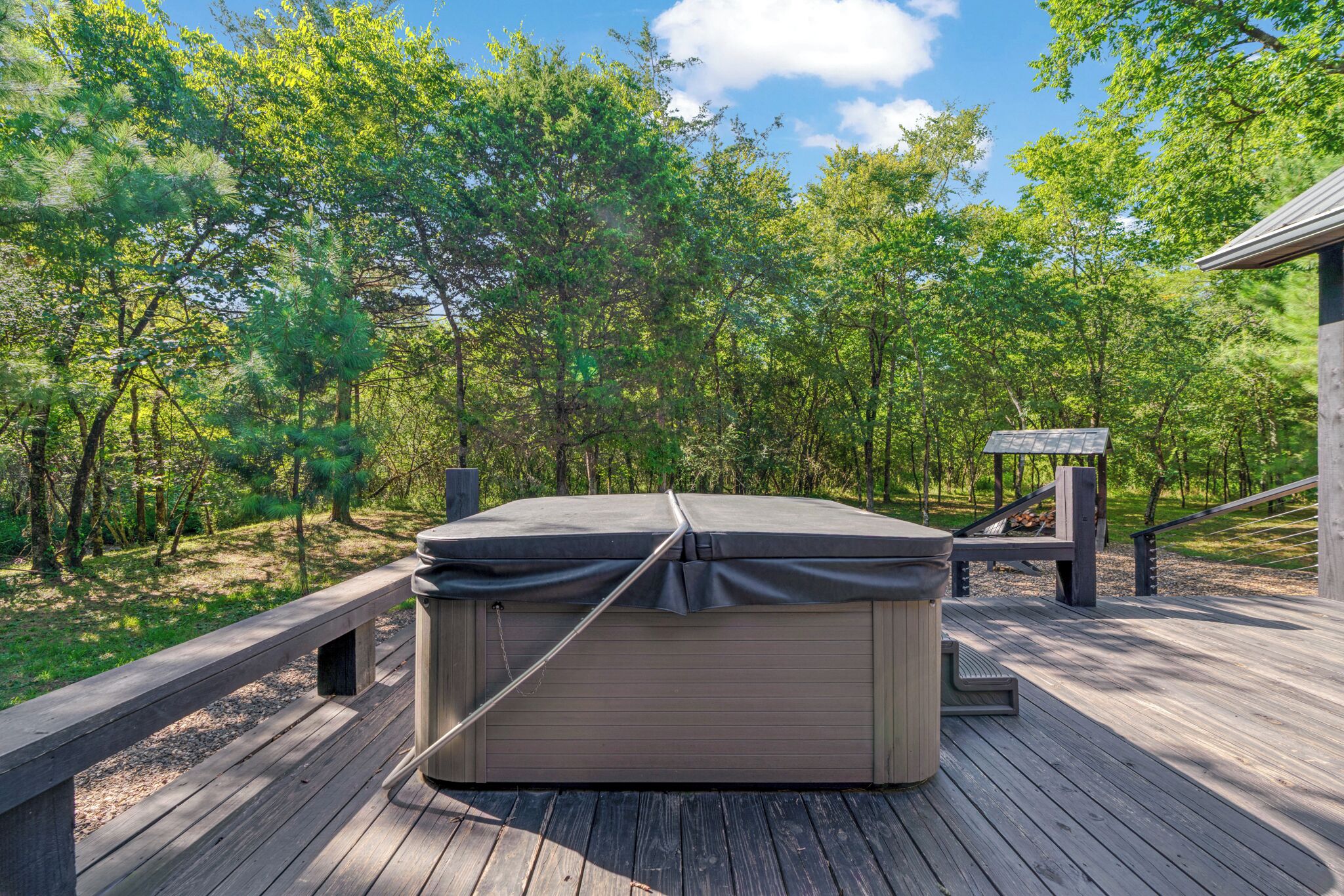 Un bain à remous sur une terrasse en bois, entouré d’arbres.