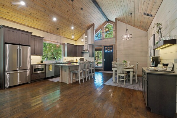 A spacious kitchen with wooden floors, stainless steel appliances, and a large island with seating.
