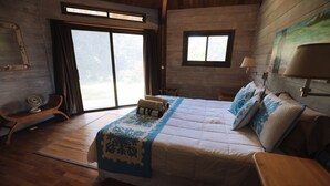 Une chambre avec un grand lit, un plancher en bois, une fenêtre et un tableau au mur.