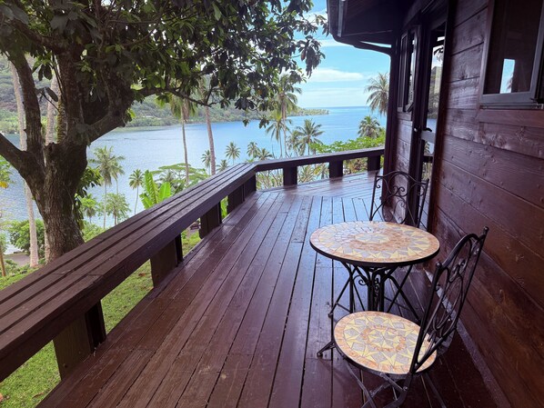 A wooden deck with a table and chairs overlooking a body of water.