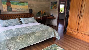 Une chambre à coucher comprenant un lit, une tête de lit en bois, une table de chevet, un bureau, une armoire et deux tableaux accrochés au mur.