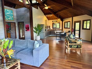 A spacious living area with a sofa, a dining table, and a kitchen in the background. - Beautiful Private Home with Stunning Views of Opunohu Bay (Opunohu Bay)