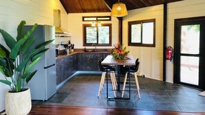 Une cuisine moderne avec un revêtement de sol en bois foncé, un îlot central et un coin repas comprenant une table et des chaises.