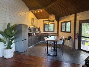 Una cocina moderna con una isla central, armarios de madera y un comedor con mesa y sillas.
