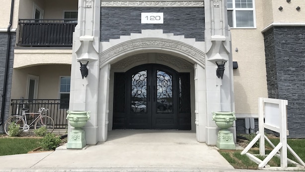 A building entrance with a black door, a balcony, and a number '120' sign. - Comfortable and Spacious 2BD, 2BA New Built Condo (Saskatoon)
