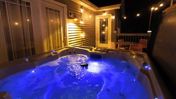 Ein Whirlpool mit schwimmender Plattform, umgeben von einer Terrasse mit Stühlen und Lichterketten.