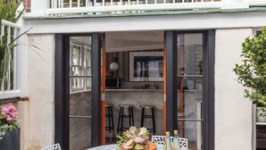 A round table with white chairs, a small bar area, and a balcony with a railing.