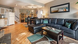 Ein modernes Wohnzimmer mit einer schwarzen Ledersofa, einem Holztisch und einem Essbereich mit einem Holztisch und Stühlen.