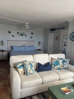 A bedroom with a bed, a nightstand, a dresser, a ceiling fan, and a wall clock.