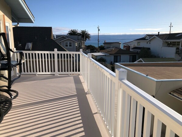 A balcony with a white railing, a table, and chairs.