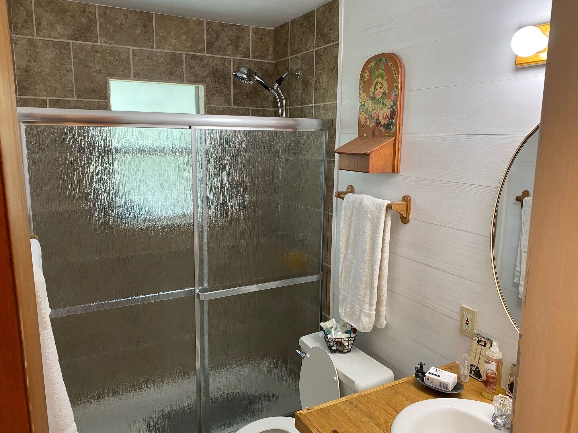 Une salle de bain avec une douche à parois de verre, des toilettes, un lavabo et un miroir.
