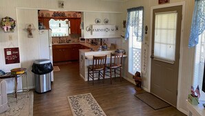 A compact kitchen with wooden cabinets, a central island, and a dining area with chairs.