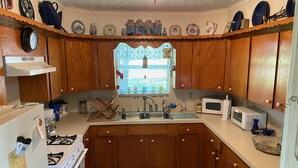 A kitchen with wooden cabinets, a stove, a sink, and a window with blinds.