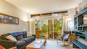 Een moderne woonkamer met een bank, fauteuils, een salontafel en een boekenplank.