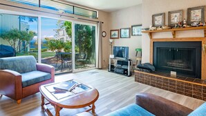 Una sala de estar con chimenea, televisor y comedor con mesa y sillas.