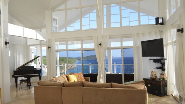 A spacious living room with a grand piano, a large sofa, and a television. - The Most Beautiful and Relaxing Oceanfront Views of Curacao (Santa Martha)