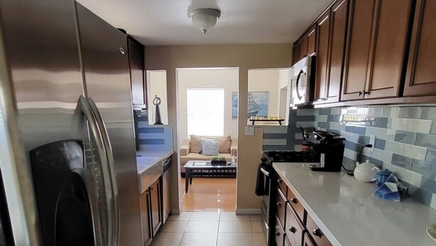 A kitchen with wooden cabinets, a stainless steel refrigerator, a microwave, and a stove. - 2BR 1BA Condo in Roosevelt Row Arts District (Phoenix)