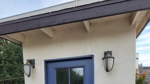 A building with a blue door, two wall-mounted light fixtures, and a small sign on the wall. - 2BR 1BA Condo in Roosevelt Row Arts District (Phoenix)