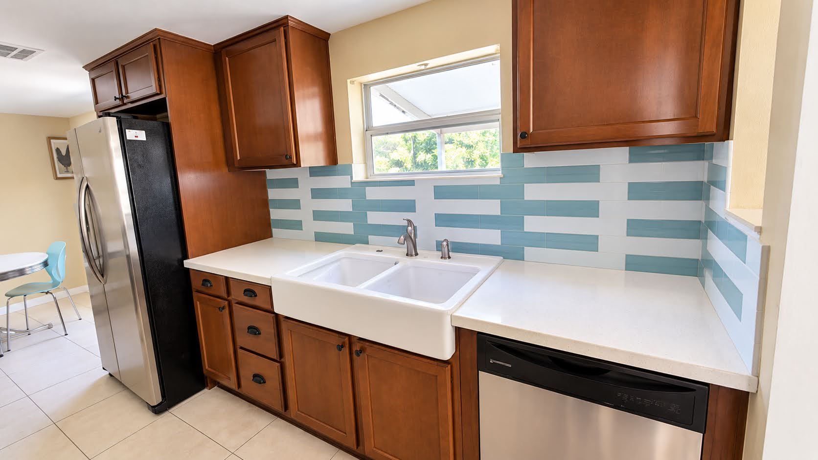 A kitchen with wooden cabinets, a stainless steel refrigerator, a double sink, and a dishwasher.