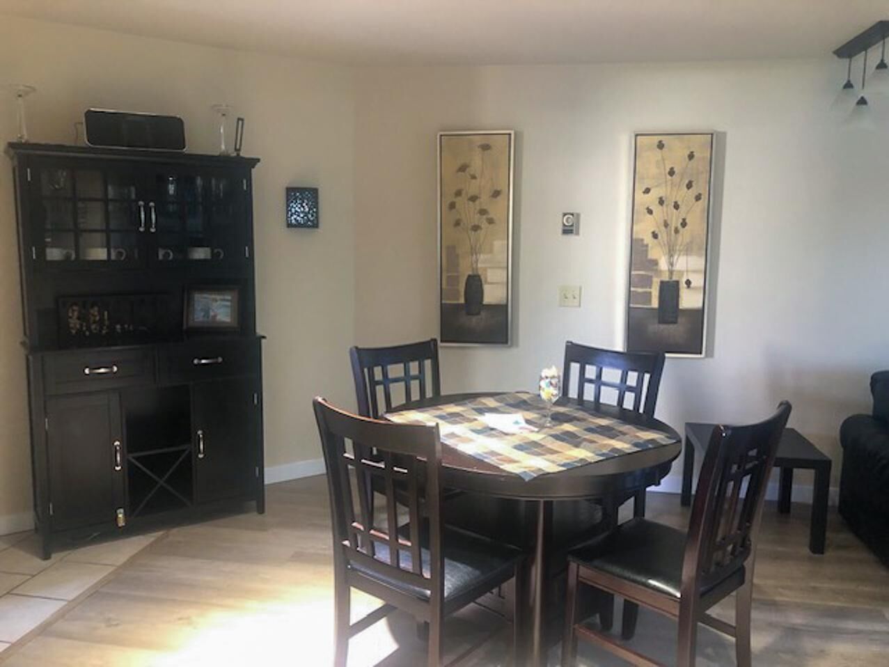 A dining area with a round table, six chairs, and a black cabinet with glass doors.