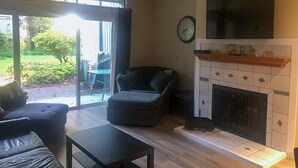 Ein Wohnzimmer mit Kamin, einer Couch, einem Sessel und einem Fernseher.