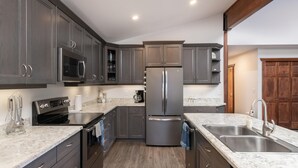 Cozinha moderna com armários cinza escuro, eletrodomésticos de aço inoxidável e bancada de mármore.