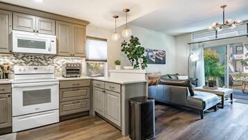 A modern kitchen with built-in appliances, a dining area with a sofa, and a view of the outdoors.