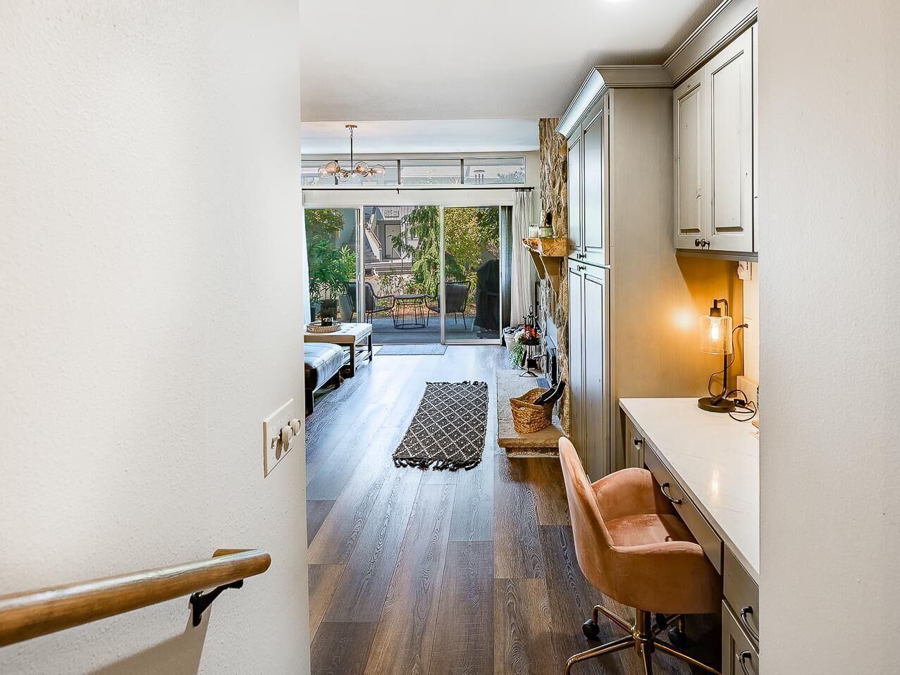A modern kitchen with a view to a patio, a wooden floor, and a dining area with outdoor seating.