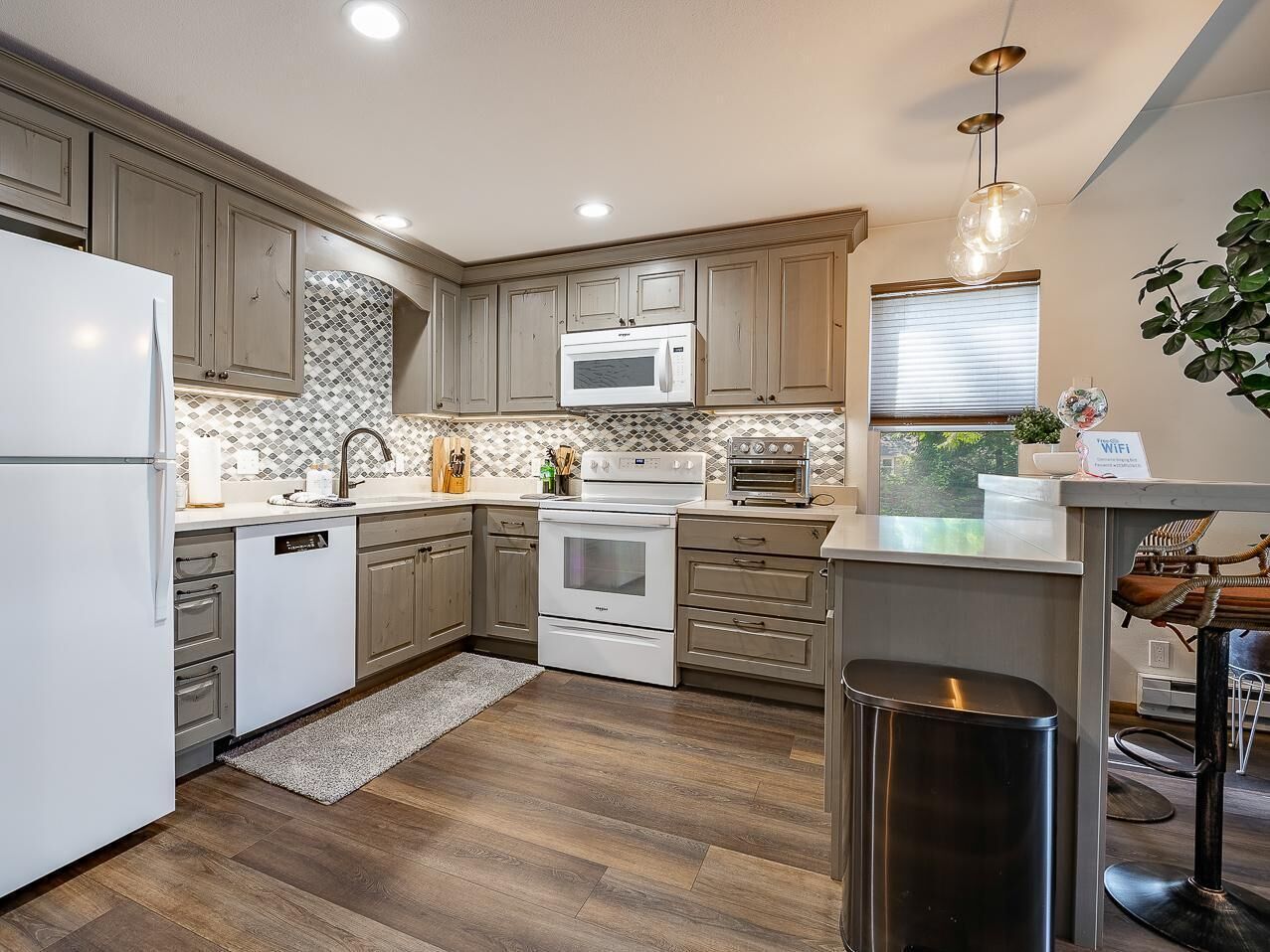 A modern kitchen with a refrigerator, microwave, oven, and sink.