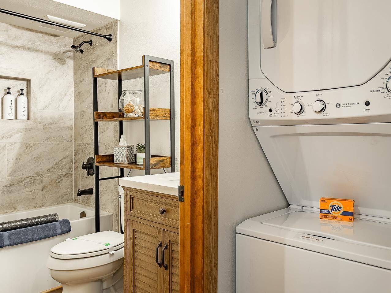 A bathroom with a bathtub, a toilet, a wooden cabinet, and a washing machine.