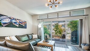 A modern living room with a leather sofa, a coffee table, and a large window with a view of a garden.