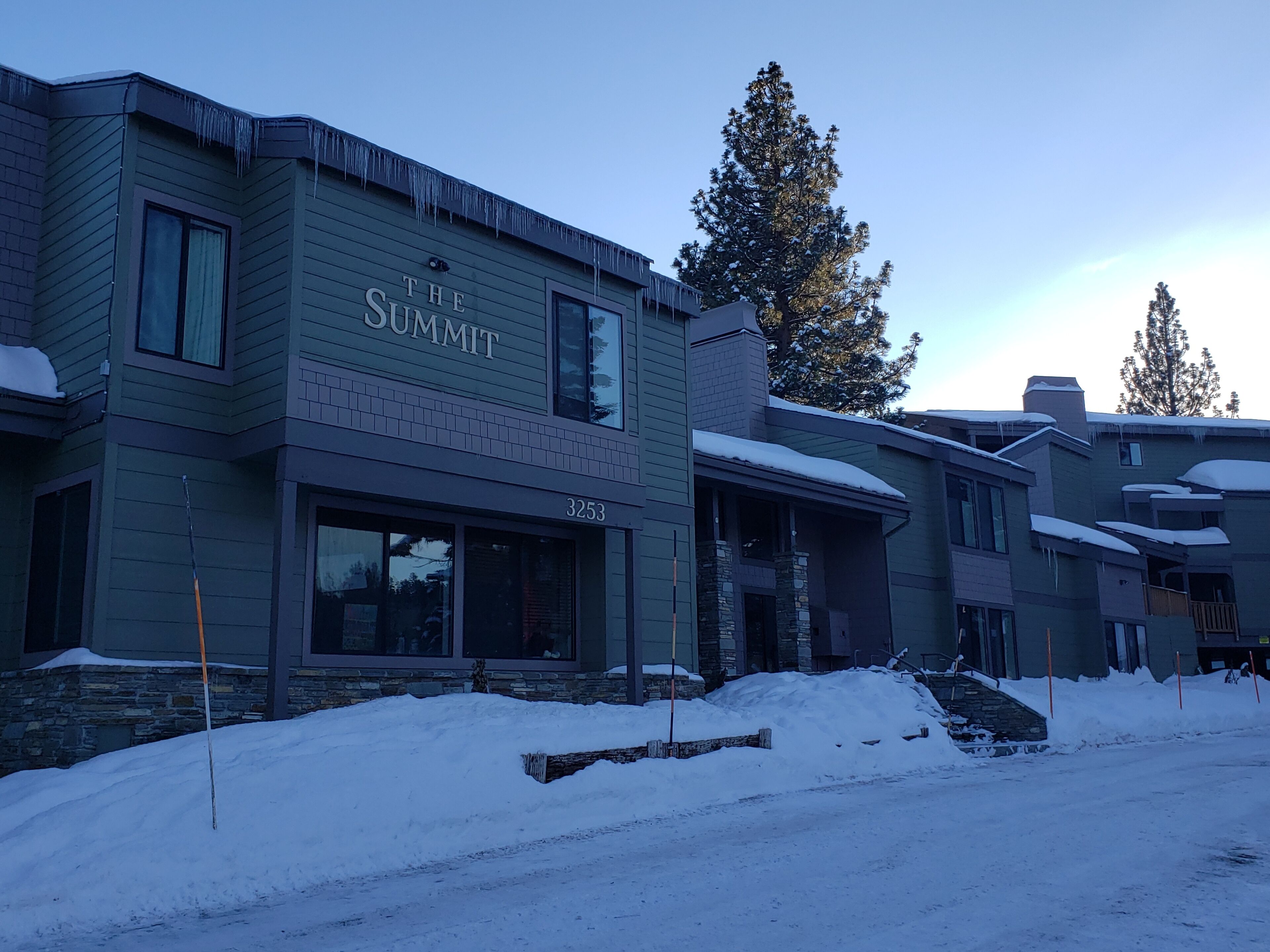 Un edificio llamado "The Summit" con fachada de piedra, ventanas grandes y techo cubierto de nieve.