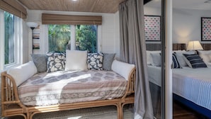 Une chambre avec un grand lit, un canapé en osier et une fenêtre avec des rideaux.