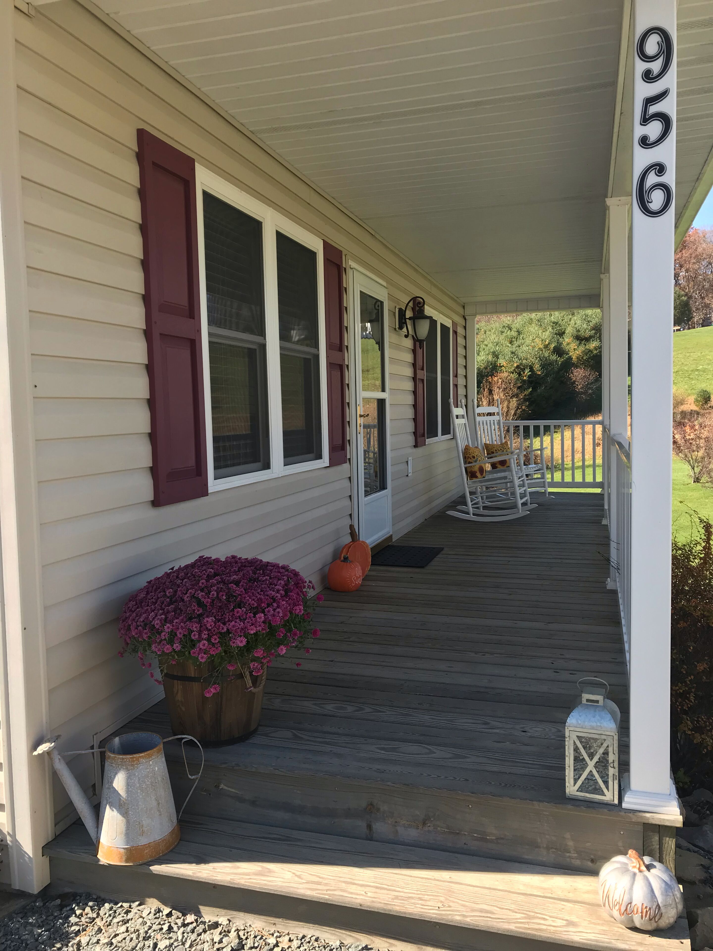 A porch with a wooden railing, a welcome sign, and a mailbox.