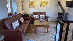 A living room with a brown leather sofa, two armchairs, a wooden coffee table, and a fireplace.