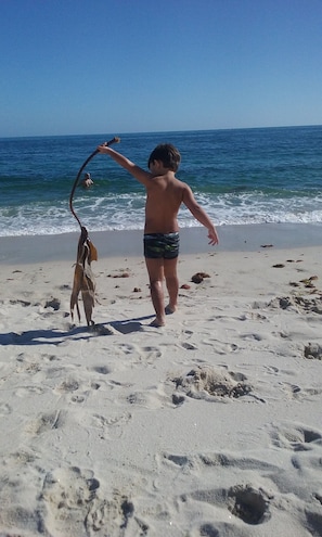 A beach scene with a child playing with a kite.