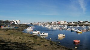 A marina with numerous boats docked, a sandy shore, and buildings in the background. - Fisherman's house a few meters from the beach (Guilvinec)