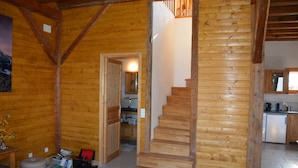 A wooden interior with a staircase leading to a second floor, a kitchen area, and a dining table with chairs.