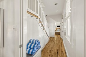 A hallway with white paneling, a wooden staircase, and a bed in the distance. - PRIVATE BEACH/POOL ACCESS -Minutes to the beach- Charming-4 Bikes Included (Rosemary Beach)