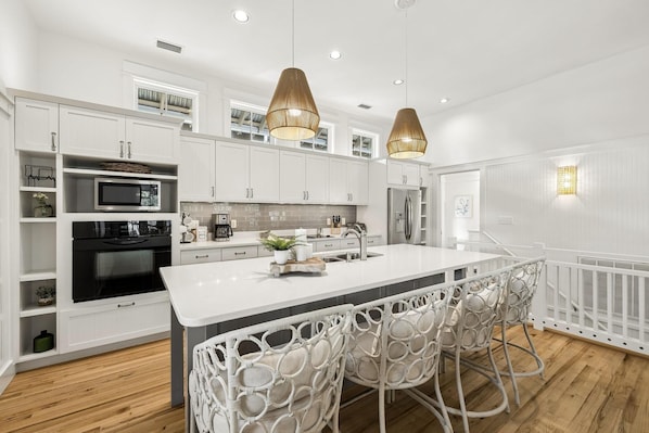 A modern kitchen with white cabinetry, a central island, and pendant lighting. - PRIVATE BEACH/POOL ACCESS -Minutes to the beach- Charming-4 Bikes Included (Rosemary Beach)
