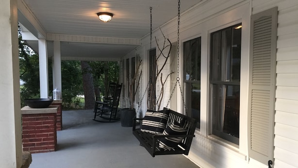 A porch with a swing chair, a rocking chair, and a planter. - Lake Lanier, Fire Pit, Fishing, Boating, Short Walk To Lake, Bring Your Boat! (Gainesville)