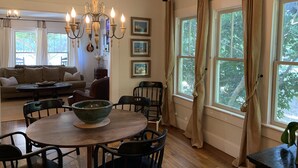 A dining area with a round table, chairs, and a chandelier. There are framed pictures on the wall and a sofa in the background. - Lake Lanier, Fire Pit, Fishing, Boating, Short Walk To Lake, Bring Your Boat! (Gainesville)