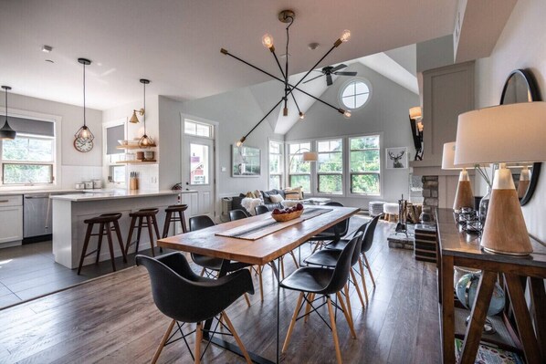 Une cuisine moderne avec un îlot central, une table à manger en bois et des chaises noires.