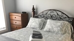 A neatly made bed with a patterned bedspread, a stack of folded towels, and a wooden nightstand with a lamp. - A small piece of South Carolina Heaven (Myrtle Beach)