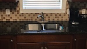 A kitchen with a window, a sink, and wooden cabinets. - A small piece of South Carolina Heaven (Myrtle Beach)