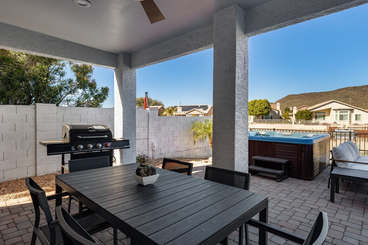 Un patio al aire libre con una parrilla, asientos y un jacuzzi.