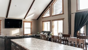Een ruime keuken met een groot eiland, houten balken in het plafond en meerdere ramen met zonwering.