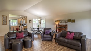 A spacious living room with leather sofas, ottomans, and a dining area with a table and chairs.
