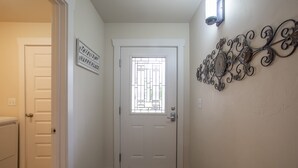 A hallway with a white door, a decorative metal wall piece, and a sign on the wall.