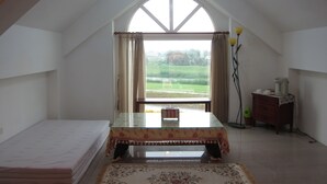 A bedroom with a glass-top table, a bed, a dresser, and a view of a green landscape through a large window. - Annong RIver Homestay (Dongshan)
